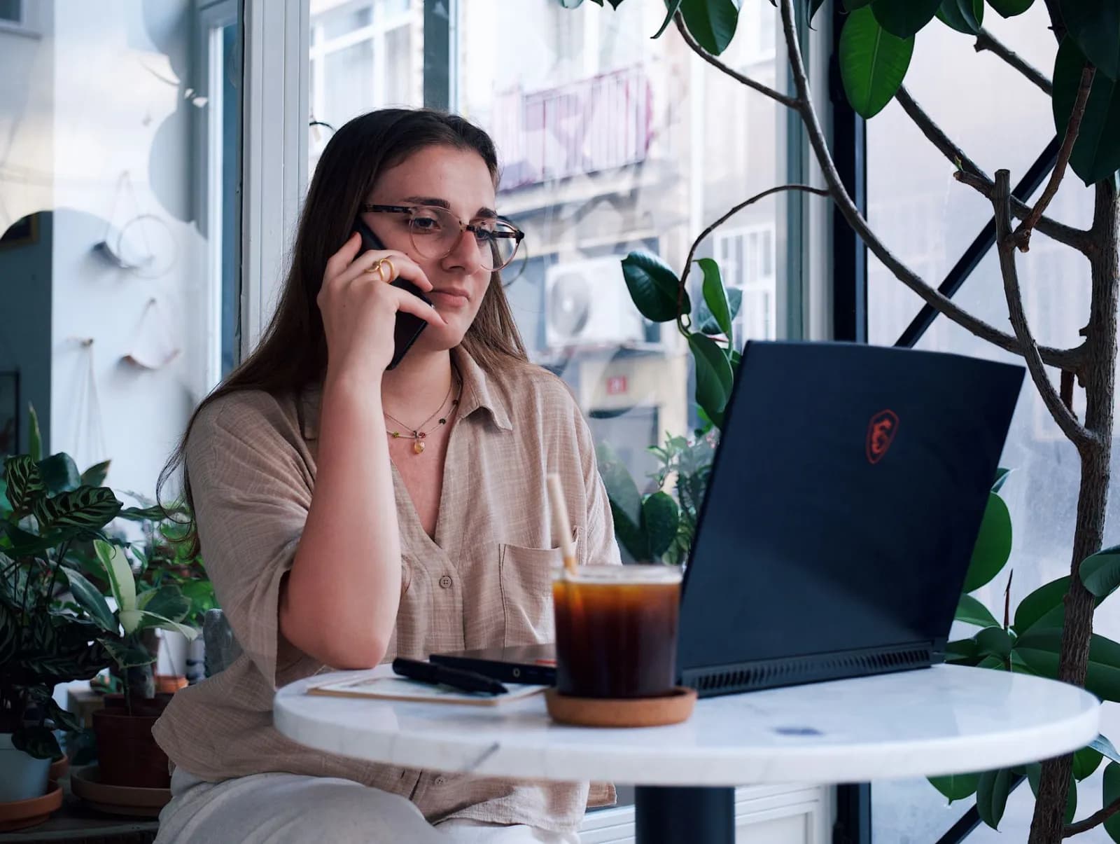 Consultora trabalhando no notebook enquanto fala ao telefone